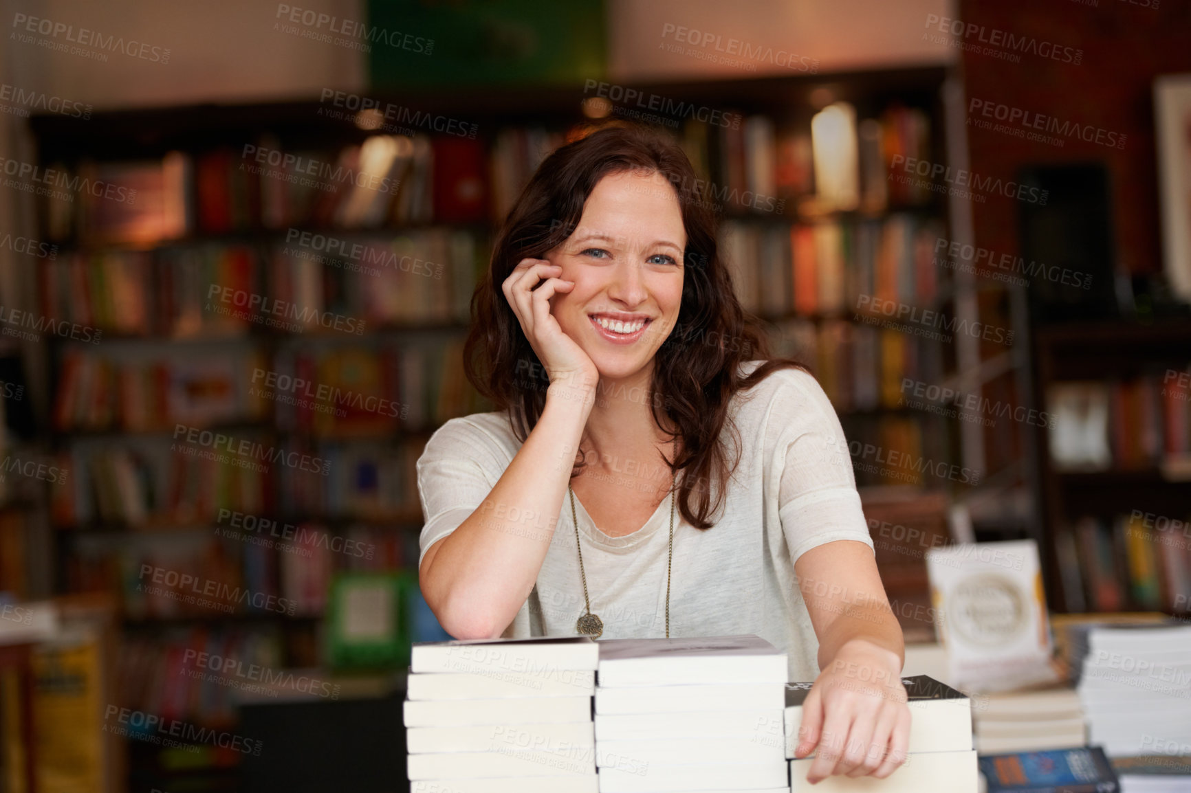 Buy stock photo Portrait of a young woman leaning on stacks of books in a bookstore