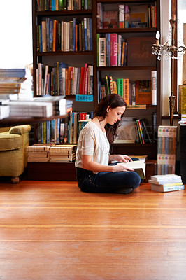 Buy stock photo A young woman sitting on the floor with her legs crossed and reading