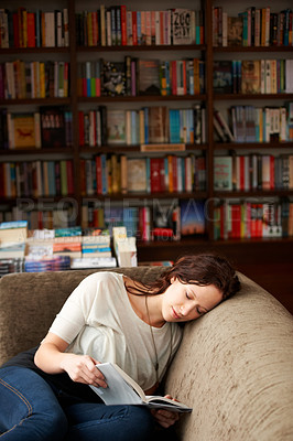 Buy stock photo Relax, literature and woman reading a story for knowledge while sitting on a sofa in library. Calm, happy and female person with a smile enjoying a fantasy book or novel on couch in bookstore or shop