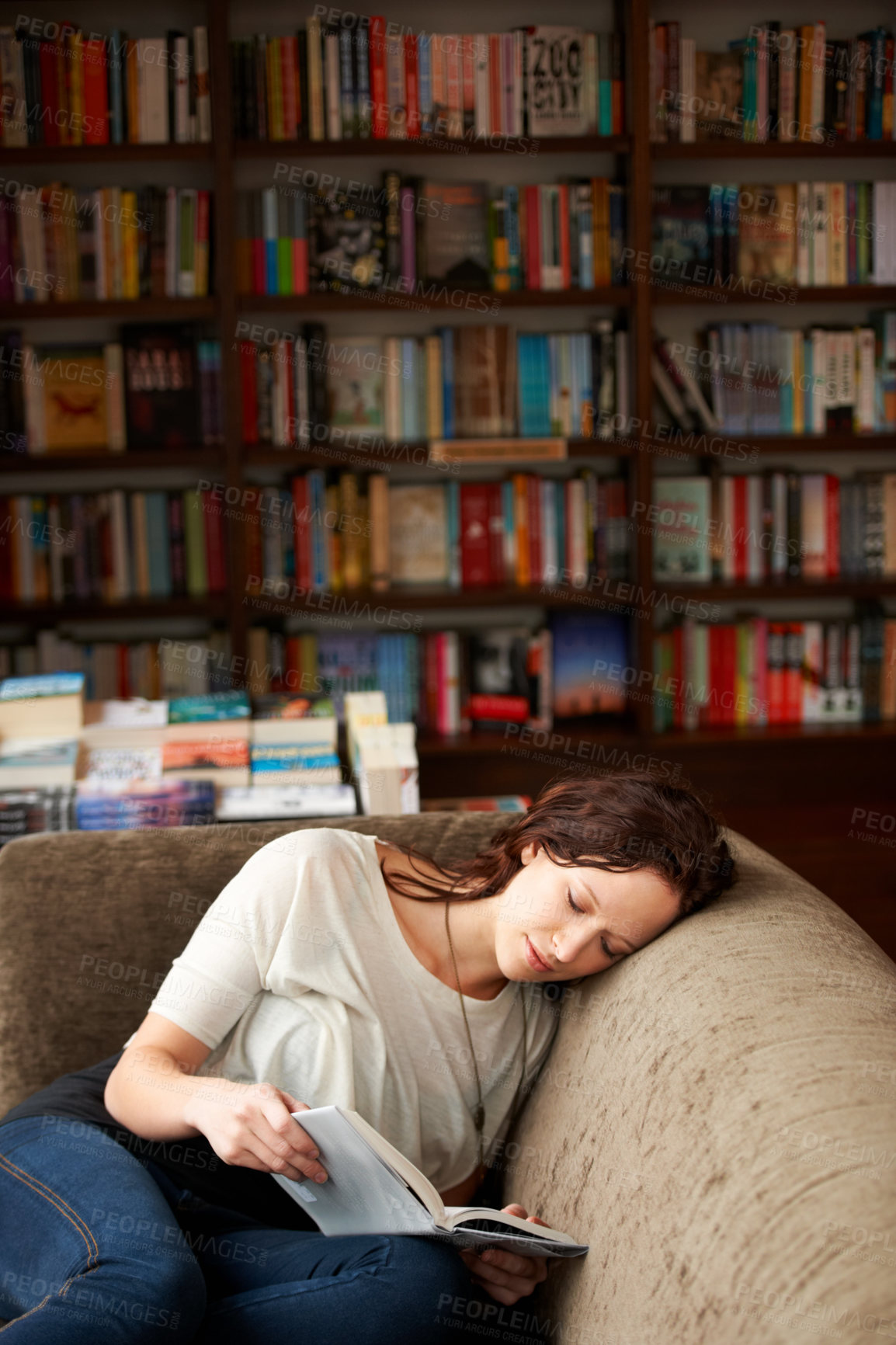 Buy stock photo Relax, literature and woman reading a story for knowledge while sitting on a sofa in library. Calm, happy and female person with a smile enjoying a fantasy book or novel on couch in bookstore or shop