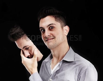 Buy stock photo Young man lifting a mask off his face and revealing a deranged expression