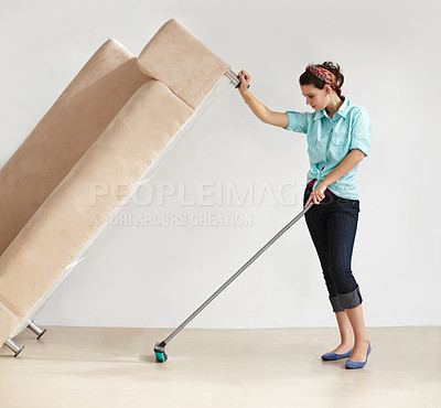 Buy stock photo Strong young woman lifting a couch and washing the floor beneath it