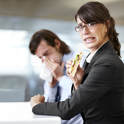Buy stock photo A businesswoman trying to eat her sandwich while a coworker blows his nose