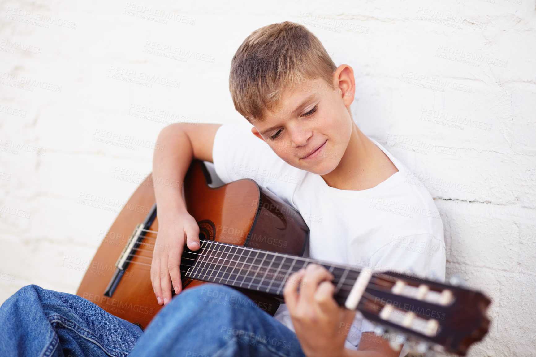 Buy stock photo Boy, guitar and smile for music lesson, talent development or learning skill practice. Male person, school child or white wall background or string acoustic instrument hobby or band, playing or rock