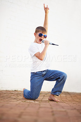 Buy stock photo Microphone, rock star and kid singing in sunglasses, creative talent and cool outdoor by wall at home. Child on mic, karaoke and music, play and recording voice, sound and kneeling for performance