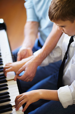 Buy stock photo Young boy playing the piano diligently alongside his tutor - cropped