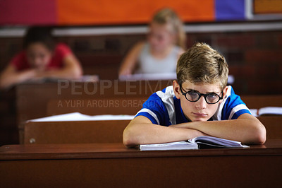 Buy stock photo Education, classroom and bored with a boy student or nerd at desk, listening to lesson for growth or development. School, book and learning with young adhd child in class to study for an exam or test