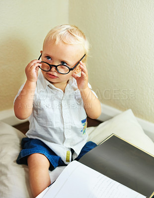 Buy stock photo Cute baby boy with spectacles sitting with a book on the floor