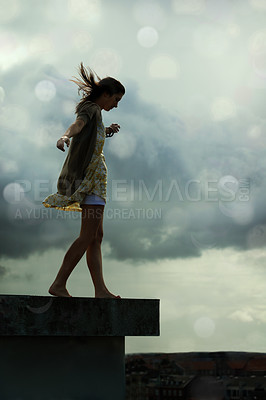 Buy stock photo Young woman walking on a rooftop with her arms outstretched
