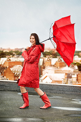 Buy stock photo Young woman laughing while being battered by rain and wind on a rooftop