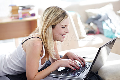 Buy stock photo Smiling young woman using her laptop while at home