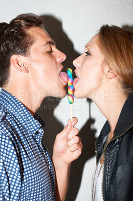 Buy stock photo Lollipop, lick and couple on a white background with snack share for love, bonding and playful. Dating, happy relationship and isolated of man and woman with sweets, sugar treats and candy in studio