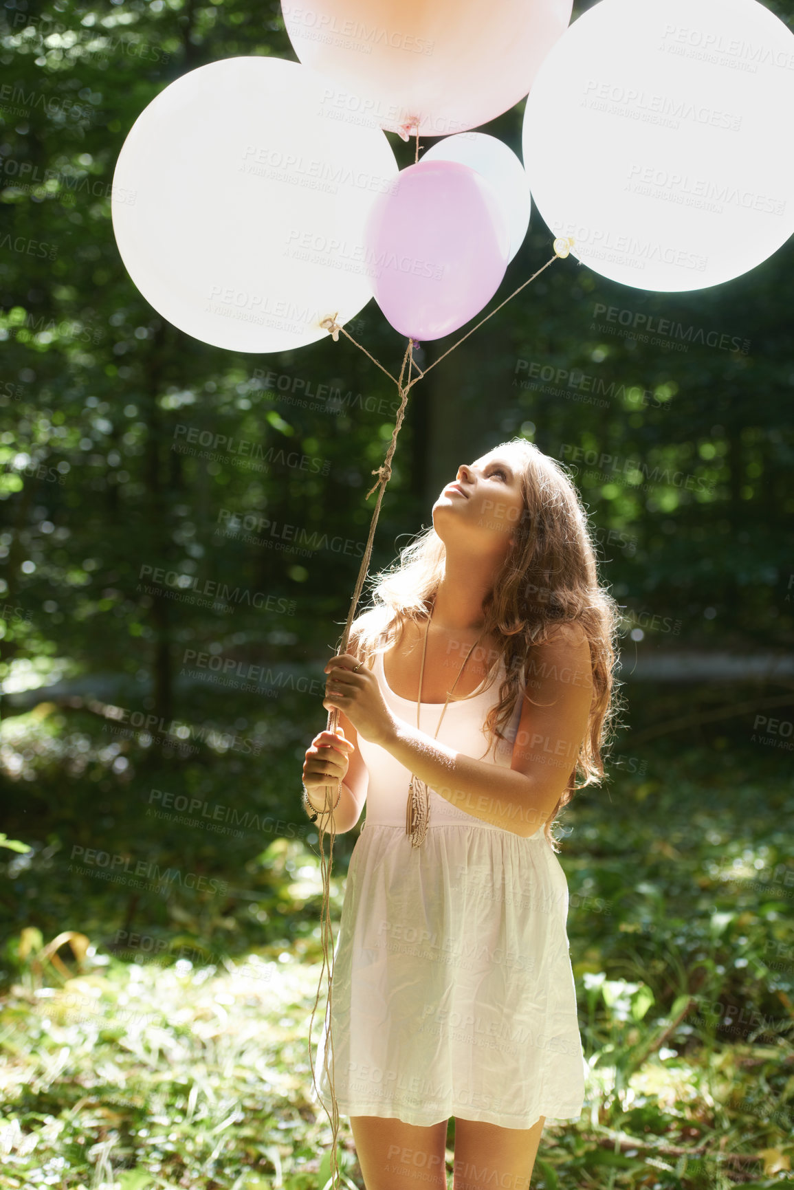 Buy stock photo Woman, holding balloons and peace in nature, playful and outdoors in forest, party decor and celebrate for freedom. Female person, sunshine and birthday in park, milestone and achievement for growth