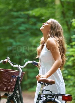 Buy stock photo A beautiful young woman walking in the forest with her bicycle