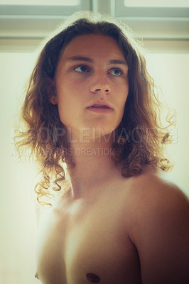 Buy stock photo A young handsome shirtless man standing next to a window