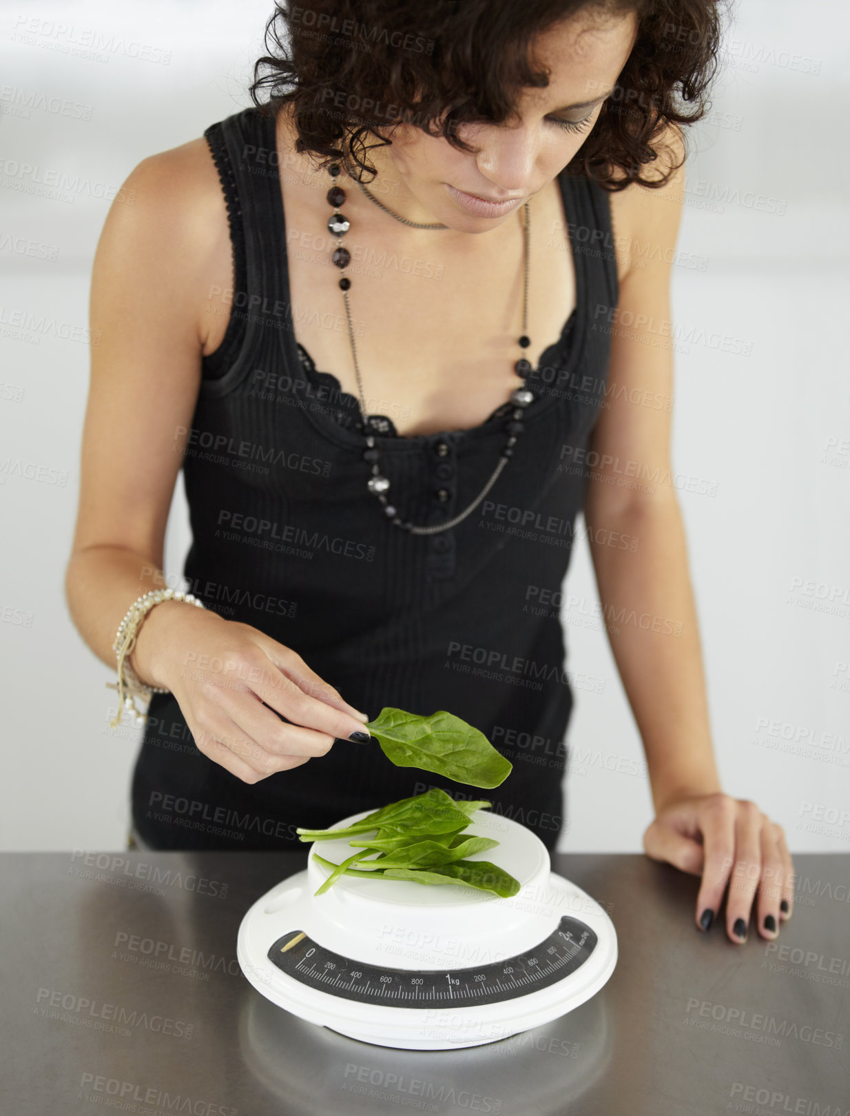 Buy stock photo Woman, scale and spinach in kitchen for food, diet or eating disorder with leaves for meal plan. Girl, mental health and vegetable leaf to lose weight with anorexia, bulimia or starving in house