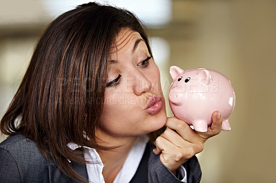 Buy stock photo An attractive businesswoman pulling a kissing face at her piggybank