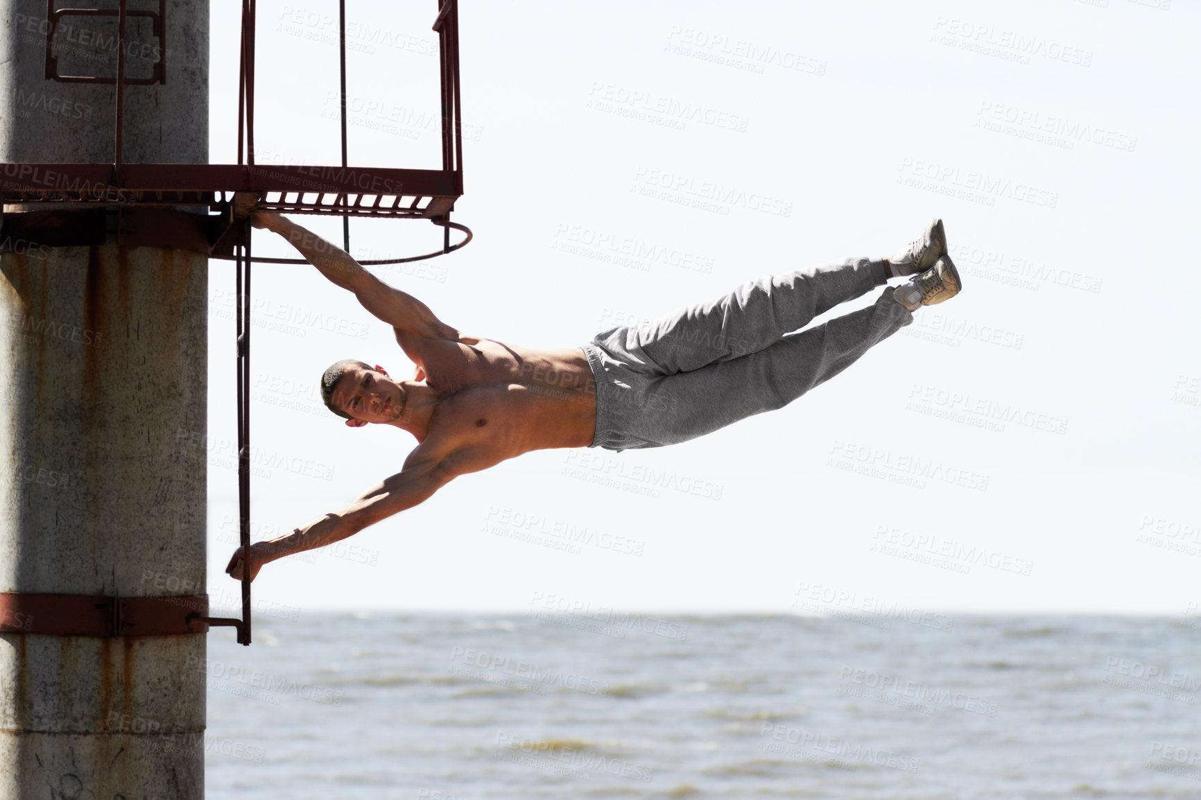 Buy stock photo A muscular young man practicing parkour at the beach