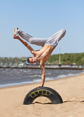 Buy stock photo A strong young man doing a breakdance move at the beach