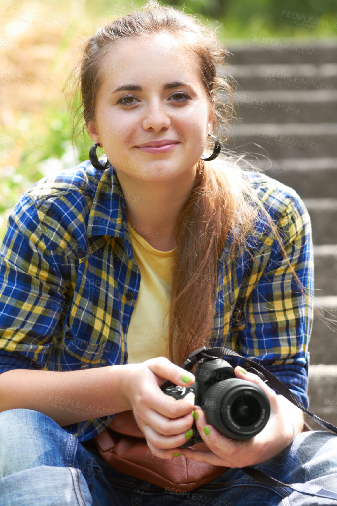 Buy stock photo A gorgeous young woman sitting on the stairs in her garden holding her camera