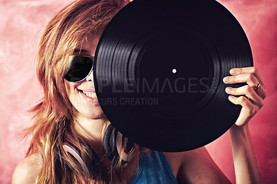 Buy stock photo Fun portrait of a young woman holding a vinyl record up to her face