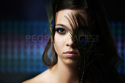 Buy stock photo Dramatic portrait of a young woman with her face partially covered by some feathers