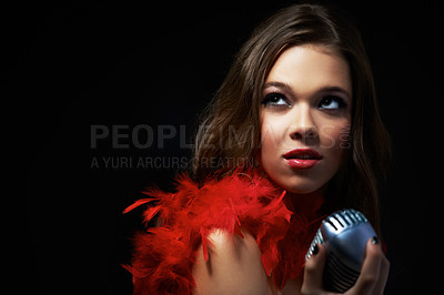 Buy stock photo Shot of an attractive young singer holding an old-fashioned microphone