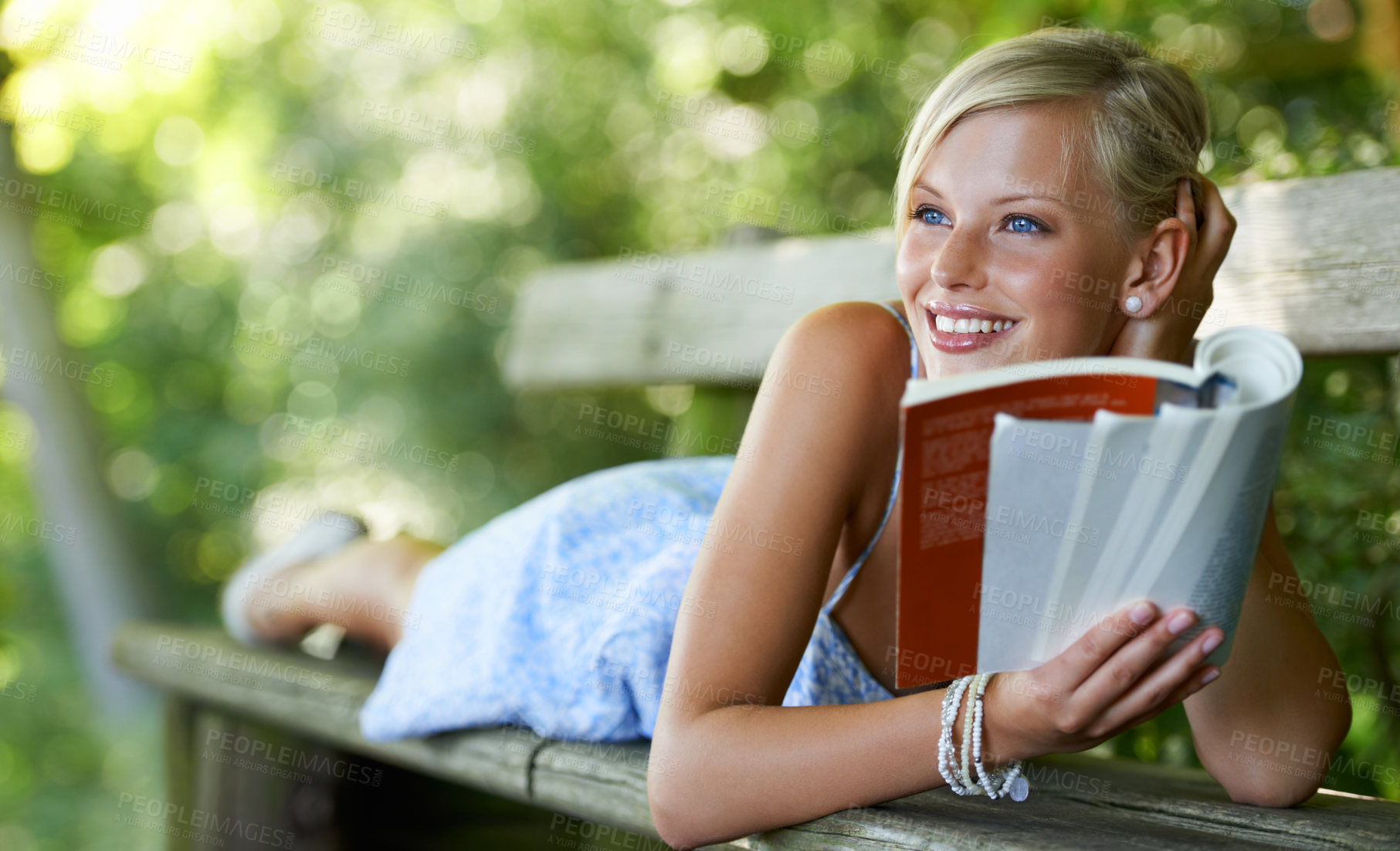 Buy stock photo Smile, relax and book with woman on park bench for literature, summer and happiness. Calm, nature and peace with young female person reading in countryside for knowledge, learning and studying