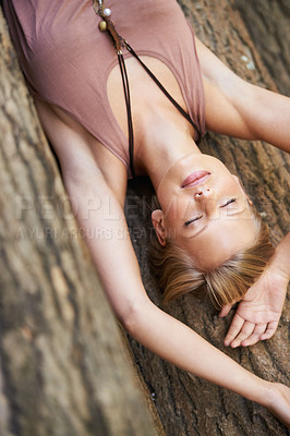 Buy stock photo A young woman lying down with her eyes closed on the forest floor