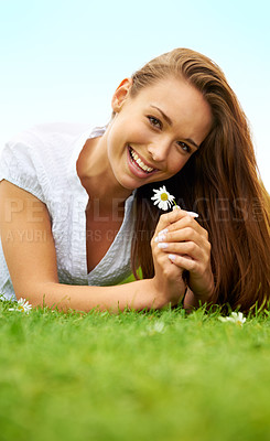Buy stock photo Portrait, happy and woman with daisy on grass, lying down on field and enjoying spring on vacation outdoor. Smile, flower plant and beauty of female person relaxing, mockup and having fun in nature.