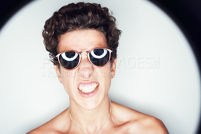 Buy stock photo Man, sunglasses and spotlight for studio portrait, fashion or shirtless with edgy punk style by background. Person, teeth and unique with halo for confidence, attitude or jewelry for trendy aesthetic