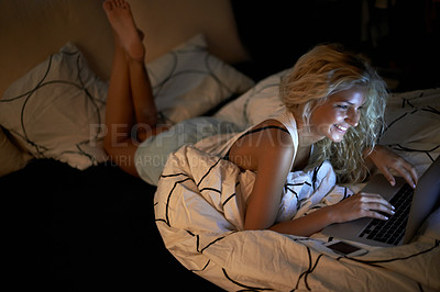 Buy stock photo Shot of a young woman using her laptop on her bed at home