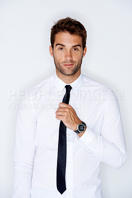Buy stock photo Handsome young guy adjusting his tie against a white background