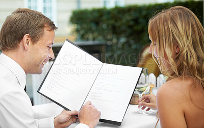 Buy stock photo Restaurant, menu and love with a couple on a date in celebration together of their anniversary. Table, reading or dating with a man and woman sitting outdoor, bonding at a fine dining venue for food