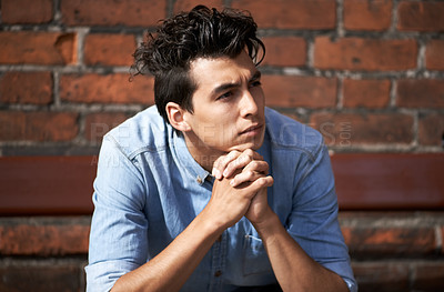 Buy stock photo A handsome young man looking away thoughtfully with his hands clasped