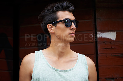 Buy stock photo Man, sunglasses and fashion in outdoors to relax, chilling and confident by wall. Male person, attitude and eyewear for style, protection and trendy on vacation, travel and holiday or adventure