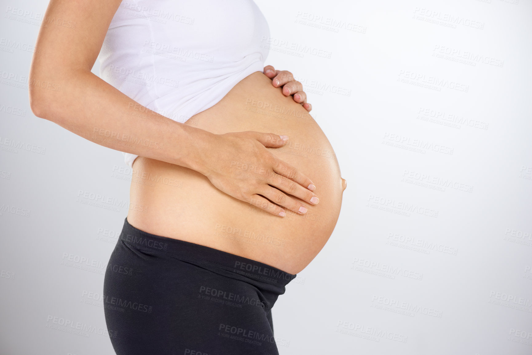 Buy stock photo Cropped profile of a pregnant woman holding her stomach affectionately