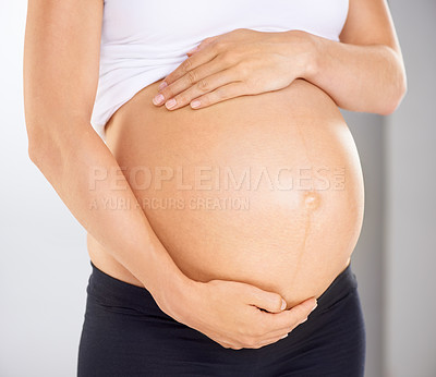 Buy stock photo Cropped image of a pregnant woman holding her stomach affectionately