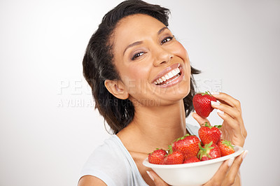 Buy stock photo Health, strawberries and young woman in a studio for wellness, nutrition and organic diet. Smile, vitamins and portrait of female person eating a fruit for healthy vegan snack by gray background.