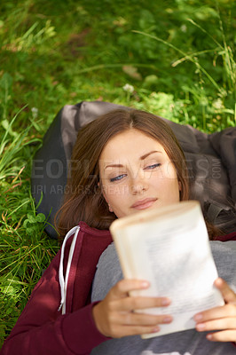 Buy stock photo Happy woman in park with book to relax at university, story or studying for school project. Above, reading and college student on grass in campus garden for research, storytelling and peace on lawn.