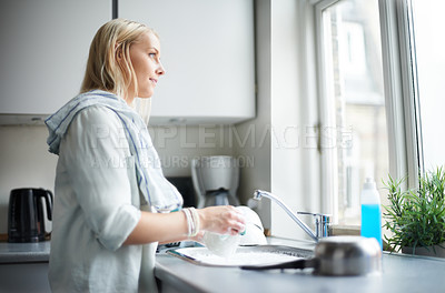 Buy stock photo A pretty young woman looking out of her window thoughtfully while doing the dishes
