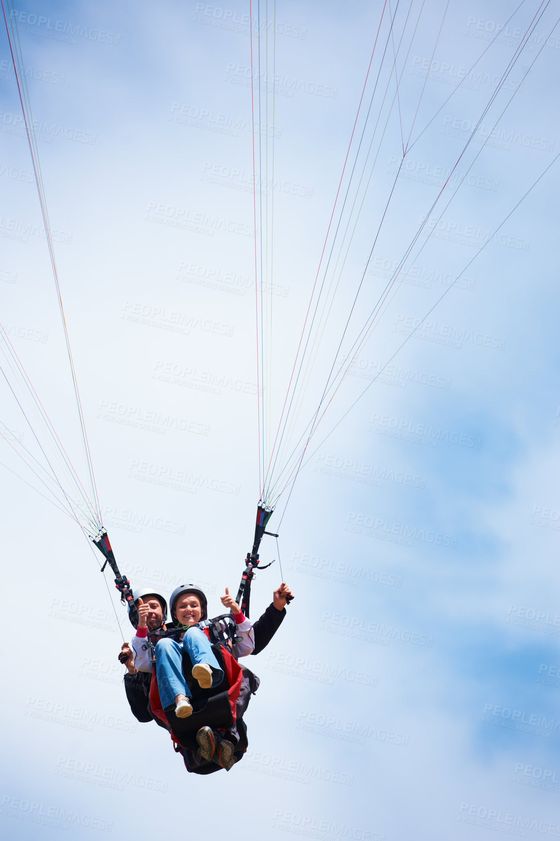 Buy stock photo Low angle shot of two people tandem paragliding and giving a thumb's up