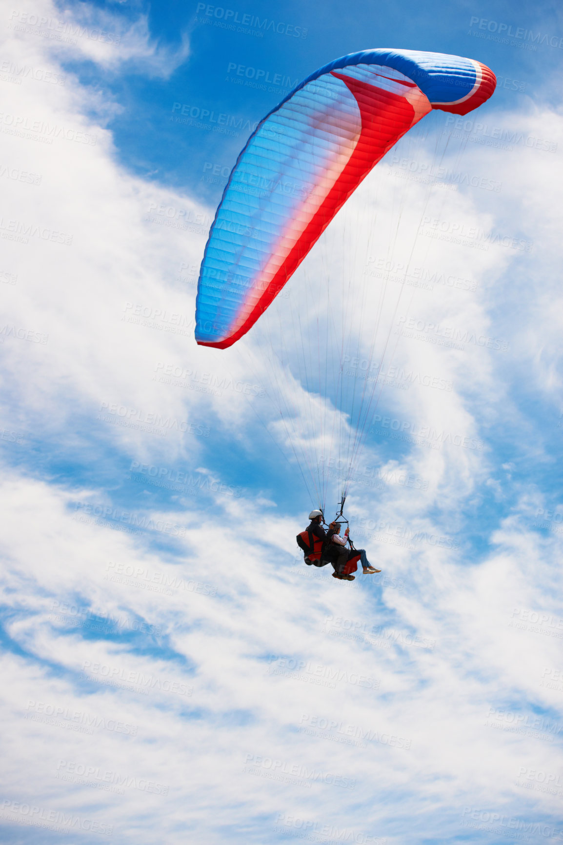 Buy stock photo Low angle view of two people doing tandem paragliding high up