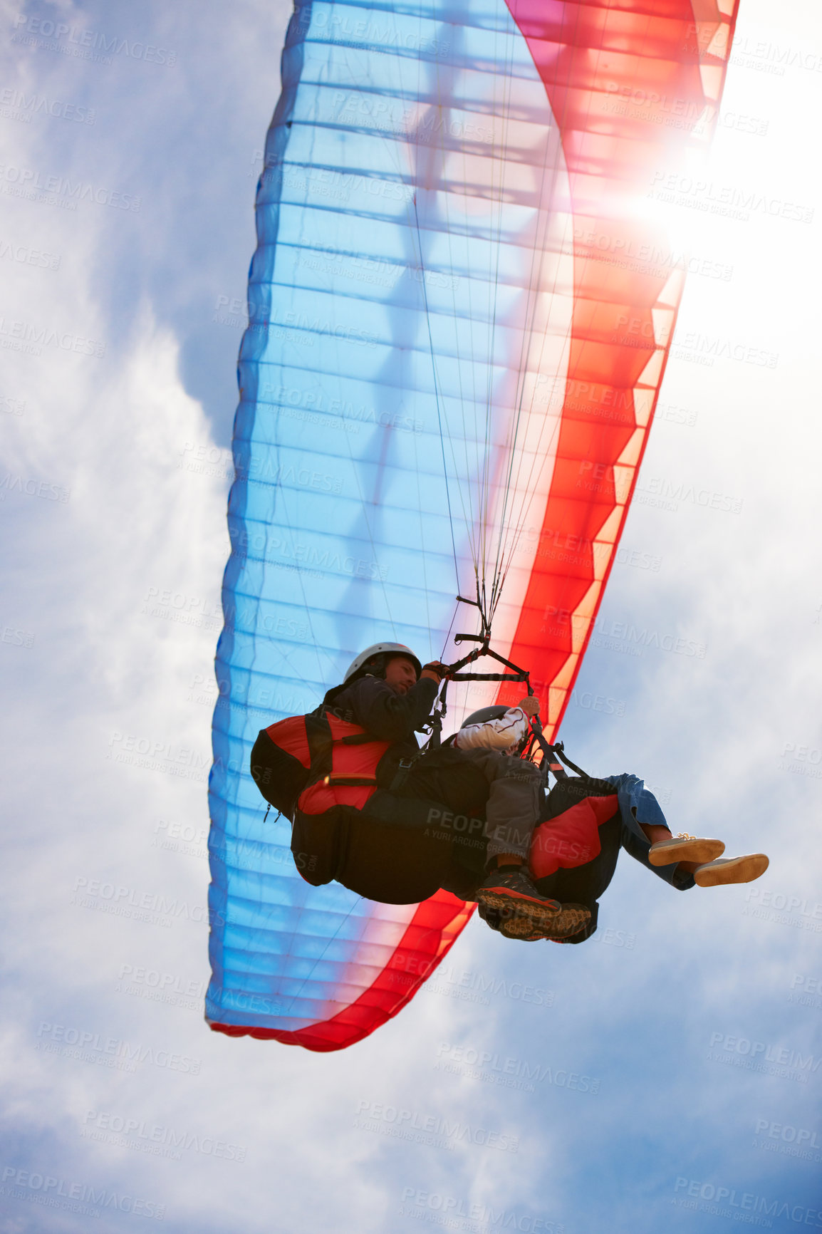 Buy stock photo People, paragliding and freedom in sky, below or extreme sport for fitness in sunshine. Coach, partnership and person on adventure, lens flare or fearless with backpack, parachute or flight in clouds