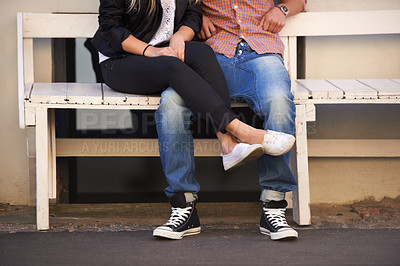 Buy stock photo A young couple being affectionate on a bench in the street