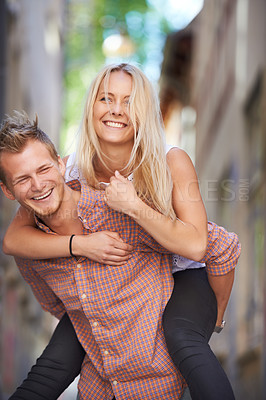 Buy stock photo A young man giving his beautiful girlfriend a piggyback ride in the street
