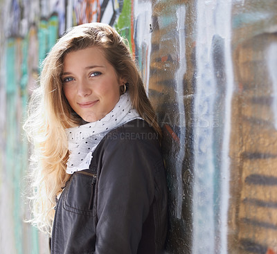 Buy stock photo Portrait, urban fashion and woman at wall with smile, graffiti and standing at outdoor street art. Happiness, youth and happy face of gen z model in city with streetwear, winter style and sunshine.