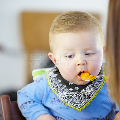 Buy stock photo Toddler, eating and meal with spoon in kitchen for lunch with baby food, carrot or squash. Little boy, infant or hungry for delicious, yummy and health in home for future, growth or child development
