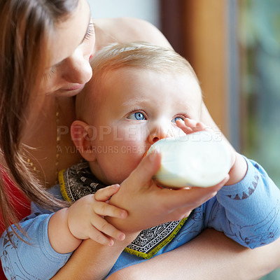 Buy stock photo Shot of a young mother bottle-feeding her baby boy