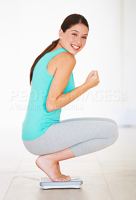 Buy stock photo Portrait of an attractive young woman crouching on a scale and looking happy